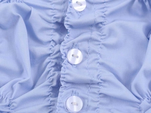 Detailed macro view of white pearlescent buttons on light blue elastic poplin shirt