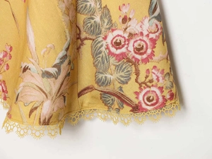 Dettaglio dell'orlo del vestito floreale giallo con stampa vintage e pizzo delicato