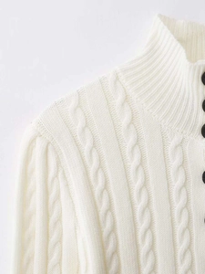 Detailansicht eines weißen Strickpullovers mit Zopfmuster, Stehkragen und schwarzen Knöpfen