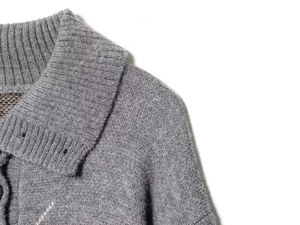 Detailansicht der weichen grauen Strickstruktur und des Rippkragens dieser Strickjacke
