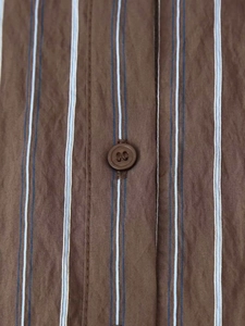 Gros plan de la chemise à rayures montrant le tissu texturé et la boutonnière
