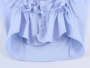 Detail view of the light blue poplin shirt featuring elastic ruffles and white buttons