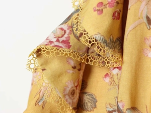 Dettaglio dell'abito floreale giallo che mostra il pizzo e la trama del tessuto