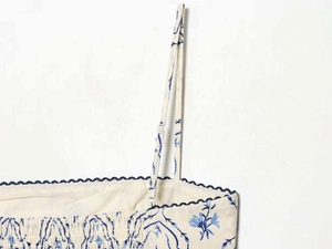 Dettaglio dei bordi smerlati blu navy su abito a fiori con spalline regolabili