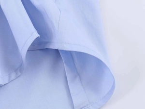 Detailed view of light blue poplin shirt featuring a curved hem and precise double stitching