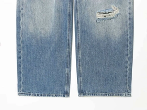 Detailaufnahme der hellblauen Jeans mit Distressed-Effekten und gewaschener Textur