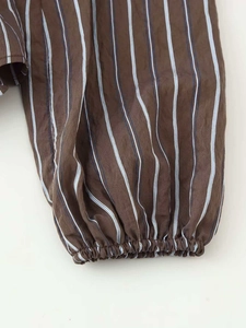 Détail des manches longues rayées marron et bleu avec poignets élastiques sur chemise