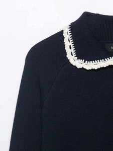 Detailed view of navy knit sweater with white floral lace trim on the lapel collar