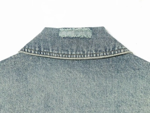 Dettaglio del colletto vintage usurato su una giacca di jeans blu chiaro da donna