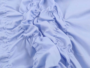 Macro detail of light blue gathered poplin fabric with fine stitching and soft pleats