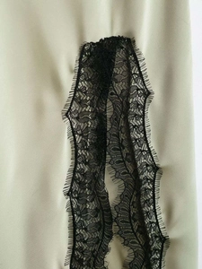 Close-up of light green dress with elegant black eyelash lace trim detail