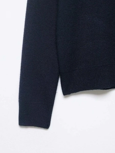 Detailed macro view of the dark blue knitted sweater's ribbed cuffs and high-quality hem