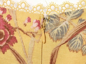Dettaglio di un vestito estivo giallo a fiori con bordo in pizzo e cerniera invisibile