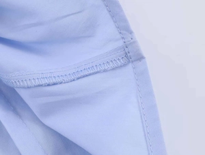 Detailed close-up showing reinforced seams and professional stitching on blue poplin shirt
