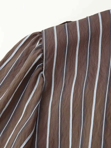 Détail de l'épaule plissée et rayures verticales sur une chemise en coton marron