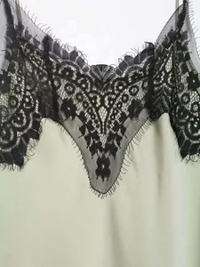 Detail of light green satin dress with intricate black floral eyelash lace trim
