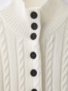 Detailaufnahme der cremefarbenen Zopfstrickjacke mit Stehkragen und schwarzen Knöpfen