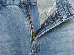 Detailansicht des Metallreißverschlusses und der Bundnaht an blauer Distressed-Jeans