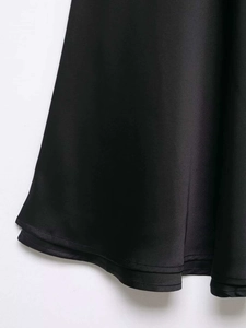 Detailed view of black satin fabric texture and neat double-stitched hem on the dress