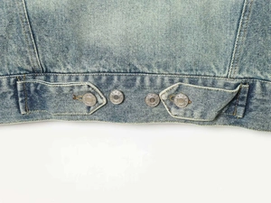 Dettaglio delle linguette regolabili in vita con bottoni d'argento su giacca di jeans