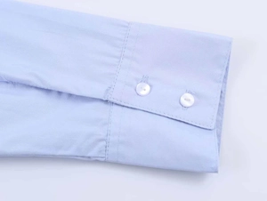 Detail shot of light blue cotton shirt cuffs featuring neat stitching and white buttons