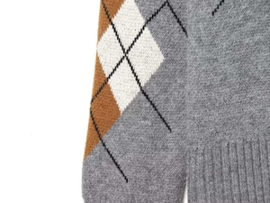 Detailaufnahme des grauen Argyle-Strickpullovers mit Rautenmuster und geripptem Saum