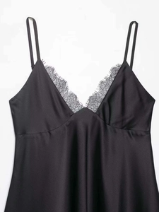 Detail shot of black satin slip dress showing delicate eyelash lace on the V-neckline