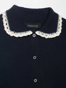 Detail of navy knit cardigan featuring a white lace Peter Pan collar and buttons