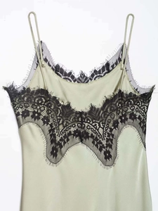 Detail of light green satin dress featuring black eyelash lace trim and thin straps
