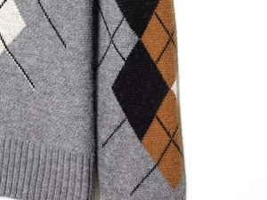 Detaillierte Nahaufnahme von Rautenmuster und Rippsaum an einem grauen Strickpullover