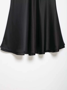 Close-up of black satin dress hem with smooth texture and high-quality stitching details