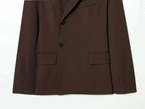 Close-up of a loose fit dark brown blazer with flap pockets and two buttons