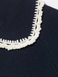 Close-up of navy knit sweater with white floral lace trim on the collar detail