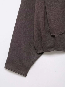 Detail of dark brown textured fabric and fine stitching on a long-sleeve jacket cuff