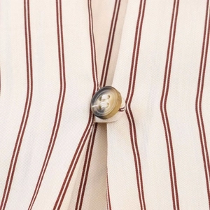 Detalle de la tela de camisa a rayas con botón de resina ámbar y rayas marrones finas