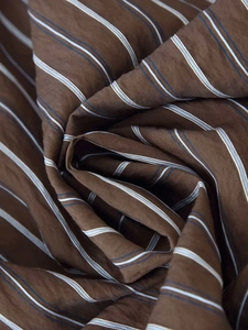 Détail du tissu rayé marron café avec des lignes bleues et blanches et une texture lisse
