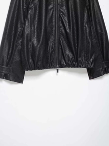 Détail du blouson aviateur en similicuir noir montrant le grain et l'ourlet élastique
