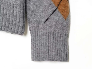 Detail von grauem Rauten-Strickpullover mit Rippbündchen und weicher Textur