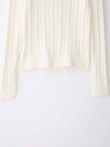 Detaillierte Nahaufnahme der weichen Zopfstrickstruktur und des Saums dieser Strickjacke