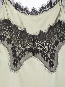 Detail view of light green satin dress with intricate black eyelash lace trim at the neckline