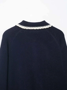 Detailed close-up of dark blue knit top featuring delicate white lace trim on the collar