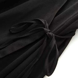 Detailed macro view of a minimalist black wrap dress with elegant side tie bow detail