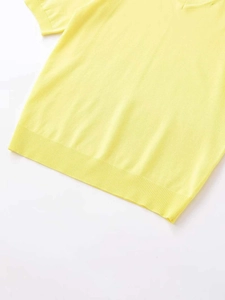 Detailed close-up of light yellow knit top with ribbed hem and soft woven texture