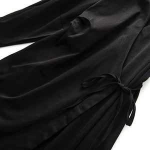 Detail view showing the side-tie knot and soft texture of this black wrap dress