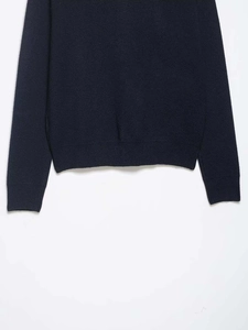 Detailed close-up showing the navy blue knitted fabric texture and ribbed hem of the sweater
