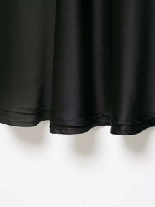 Detail of the hem stitching and silky black satin fabric on a V-neck slip dress