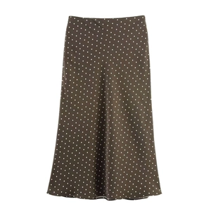 Detailed close-up of dark brown polka dot satin skirt featuring premium draped texture