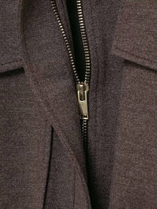 Detailed macro view of heavy textured dark gray fabric and metallic gold zipper closure