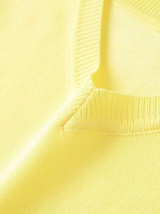 Close-up of a pale yellow V-neck knit top showing the fine ribbed texture and soft fabric