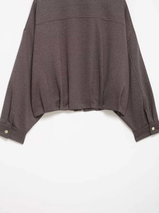 Detail of dark brown jacket with golden buttons on sleeves and metallic zipper closure